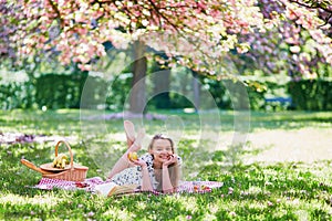 Beautiful young woman having picnic in blooming spring park