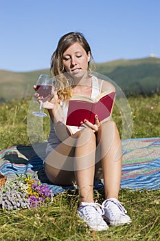 Beautiful young woman having picnic on meadow, reading book, smi