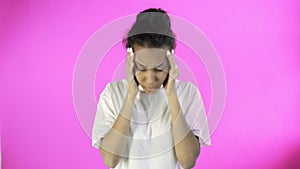 Beautiful young woman having terrible headache on pink background