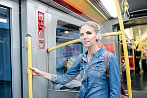 Beautiful young woman with headphones in subway train photo
