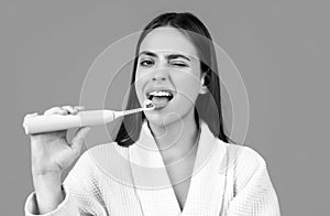Beautiful young woman with healthy teeth, beautiful female smile. Electric toothbrush. Close-up of young woman is