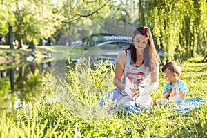 Beautiful young woman and her adorable little son play in sunny park, read books