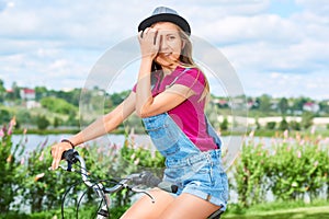 Beautiful young woman with her bicycle at the park