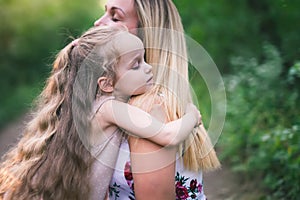 Beautiful young woman and her charming little daughter are hugging