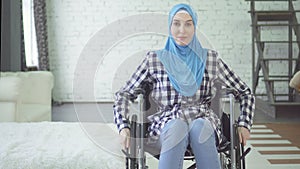 Beautiful young woman in hijab disabled person, wheelchair, in apartment
