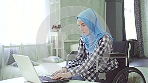 Beautiful young woman in hijab disabled person, wheelchair, work at computer