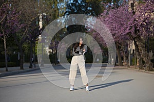 Beautiful young woman, Hispanic, brown hair, wearing striped sweater, linen pants, arms crossed, independent and empowered,