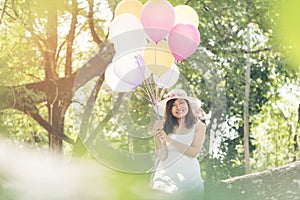 Beautiful young woman holding air balloons in garden