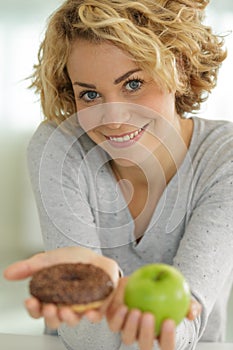 beautiful young woman holding apple and donut