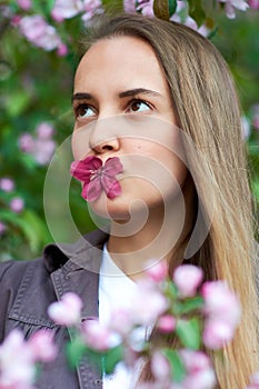 Beautiful young woman holding an apple tree flower in the park