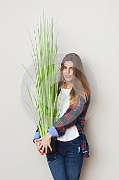 Beautiful young woman holding big green plant