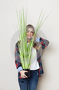 Beautiful young woman holding big green plant