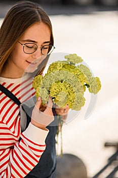 beautiful young woman holding bouquet of fresh light green carnation in her hands