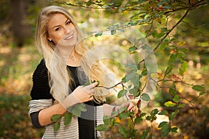 Beautiful young woman holding a branch with green leaves in the forest