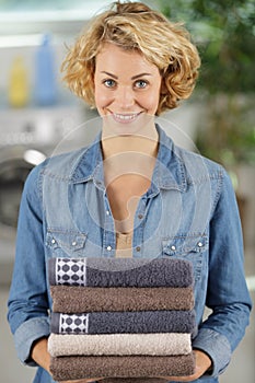 Beautiful young woman holding clean towels