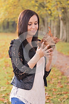 Beautiful young woman holding colorful autumn leaves in hands