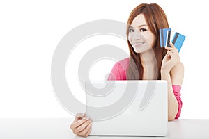 Beautiful young woman holding credit card with laptop