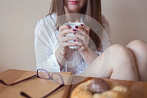 Beautiful young woman holding a cup of coffee in her hands