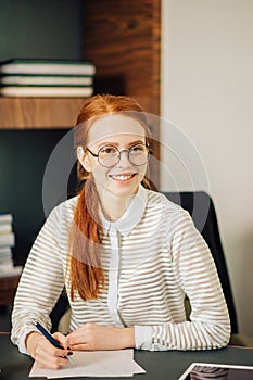 Beautiful young woman holding digital tablet and looking at camera with smile