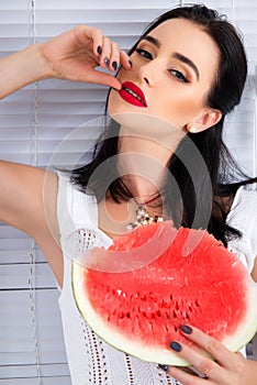 Beautiful young woman holding and eating slice of ripe red fresh juicy watermelon