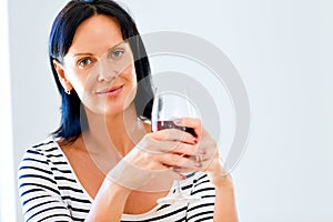 Beautiful young woman holding glass with red wine