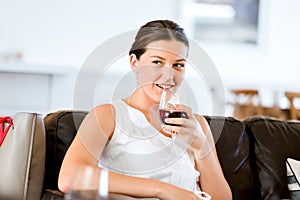 Beautiful young woman holding glass with red wine