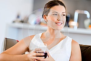 Beautiful young woman holding glass with red wine