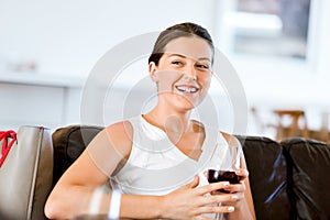 Beautiful young woman holding glass with red wine