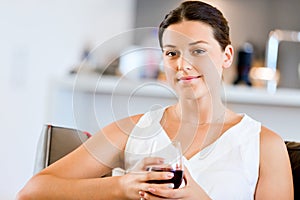 Beautiful young woman holding glass with red wine