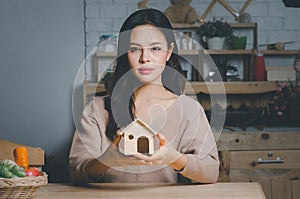 Beautiful young woman holding house model