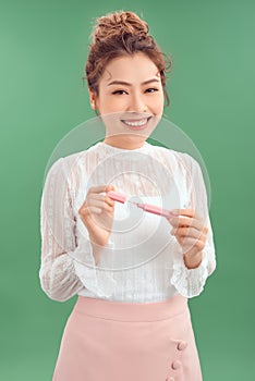 Beautiful young woman holding lipstick, isolated on green background