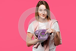 beautiful young woman holding rotary phone and smiling at camera isolated