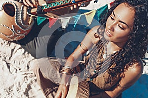 Beautiful young woman holding shaman drum and playing ethnical music