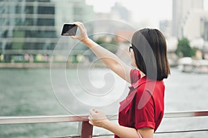 Beautiful young woman holding a smartphone. In order to take a picture of yourself from a camera phone Selfie. Tourism concept