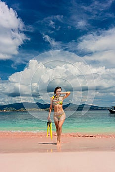 Beautiful young woman holding snorkeling equipment at Pink Beach