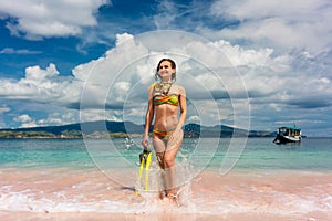 Beautiful young woman holding snorkeling equipment at Pink Beach