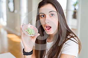 Beautiful young woman holding spicy asian wasabi scared in shock with a surprise face, afraid and excited with fear expression