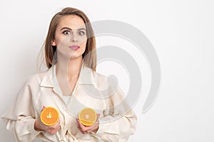 Beautiful young woman holding two half pieces of orange