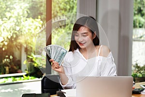 Beautiful young woman holding us dollar money. business, finance, saving, banking and online shopping concept