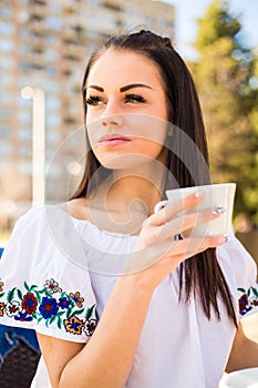 Beautiful young woman holding white cup of coffee