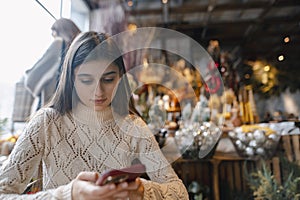 A beautiful young woman holds her phone while browsing the decor store.