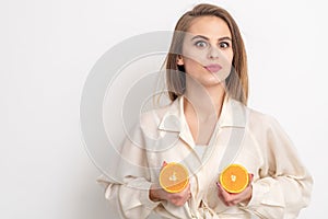 Beautiful young woman holds two halves of oranges