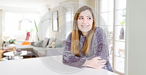 Beautiful young woman at home smiling looking side and staring away thinking