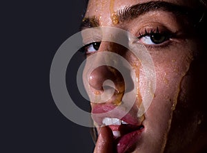 Beautiful young woman with honey on her face. Close up portrait of girl with a honey facialmask closeup. Beautiful woman