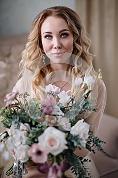 Beautiful young woman in a house dress in the boudoir, decorated with beautiful flowers, sitting on a white bed with a canopy, fas