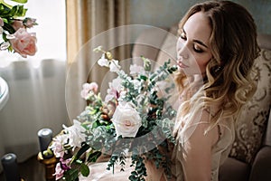 Beautiful young woman in a house dress in the boudoir, decorated with beautiful flowers, sitting on a white bed with a canopy, fas