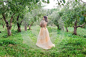 Beautiful young woman is hugging herself and standing between the trees