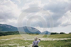 Beautiful young woman in a jeans dress and straw hat posing in a camomile field