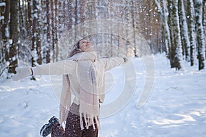 Beautiful young woman joyfully tossing snow