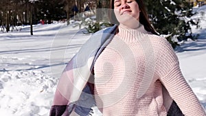 Beautiful young woman in knitted sweater in winter park. Cold weather outdoors. Snow Happy smiling portrait of girl